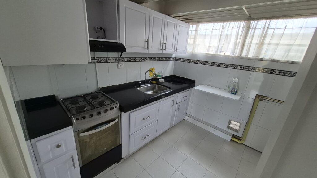 Cocina integral del apartamento, con estufa de gas, campana y mesón en L